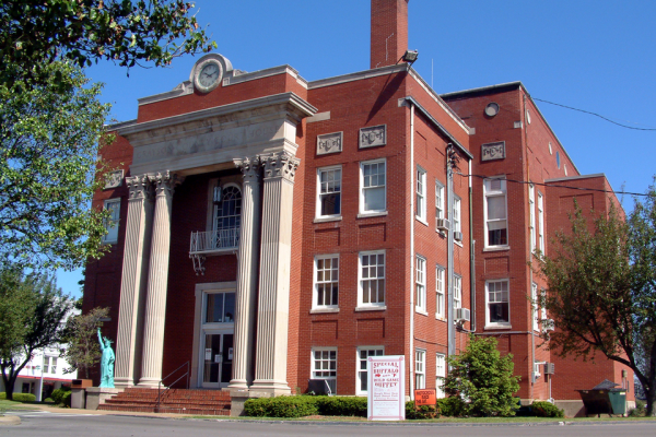 A three story red brick building with white columns on the front